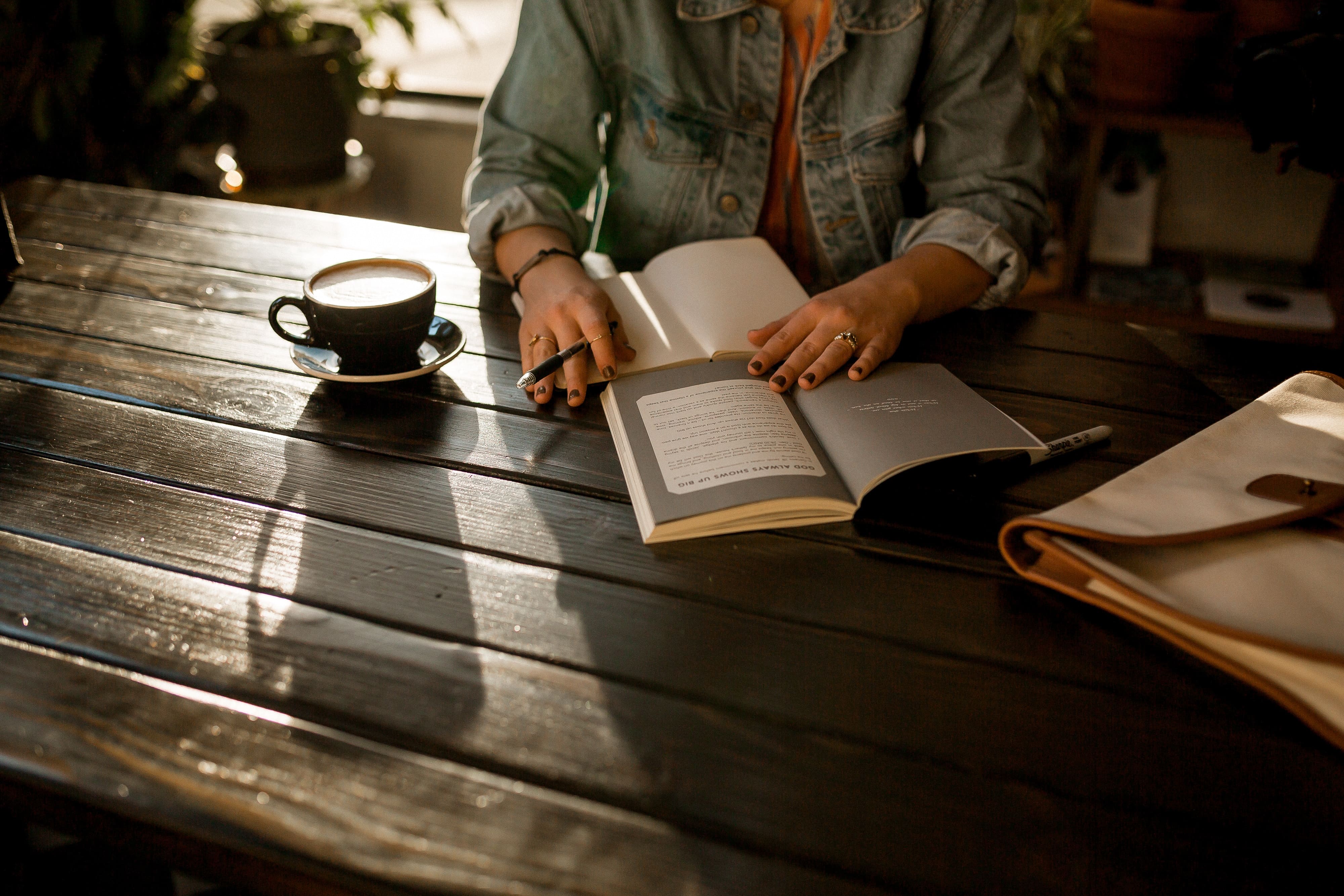 the girl writing in her notebook at the table outdoors