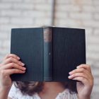 a girl covers her face with a book
