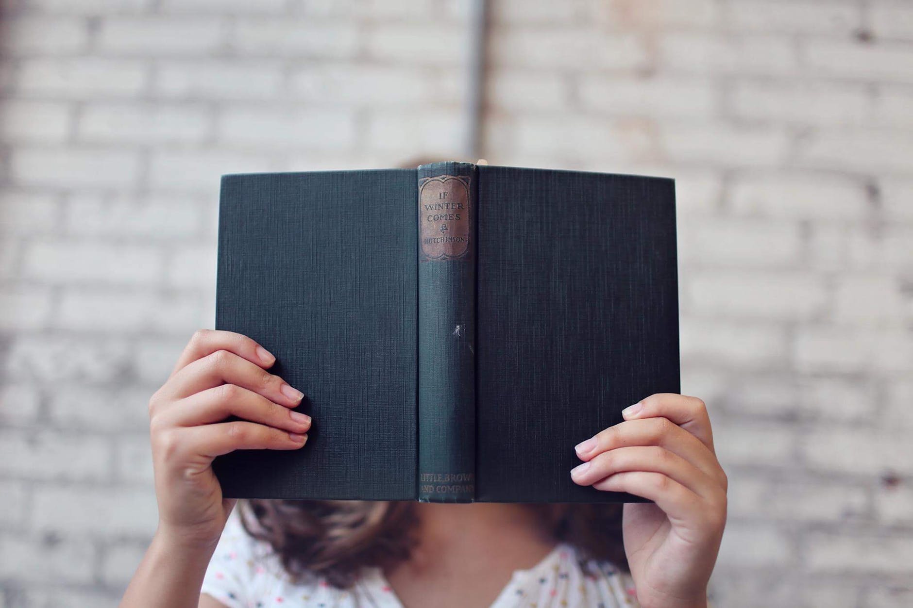 a girl covers her face with a book