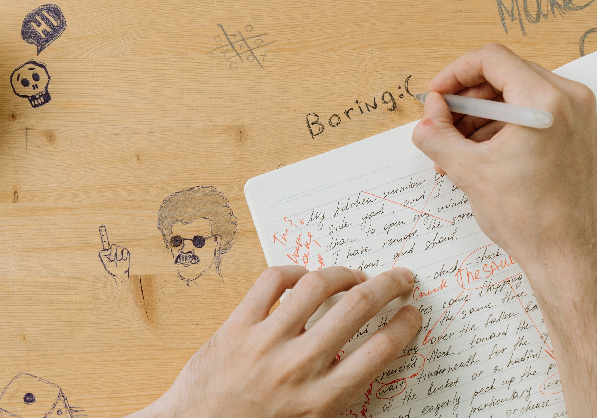 a boy is writing word boring on a desk