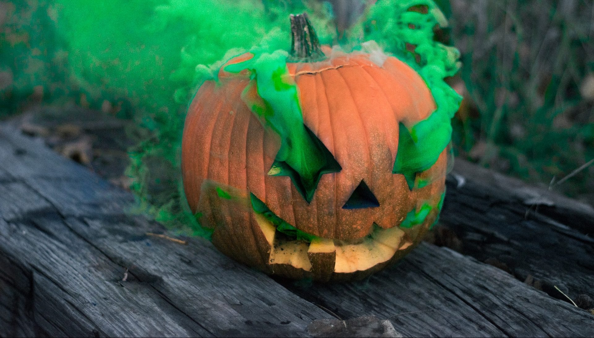 carved pumpkin in a green smoke